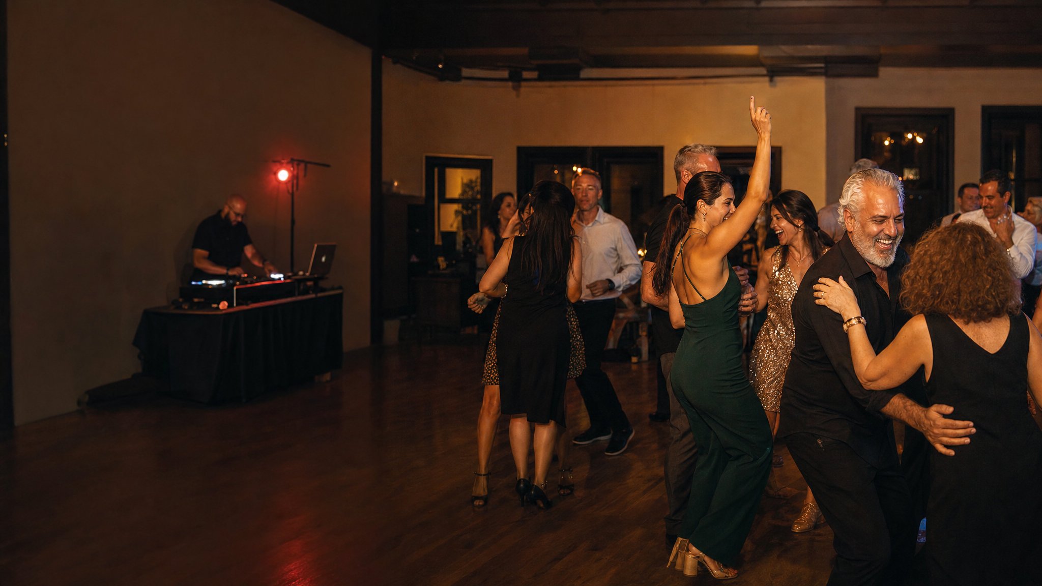 Friends celebrating together on a dance floor while a DJ plays at a private party