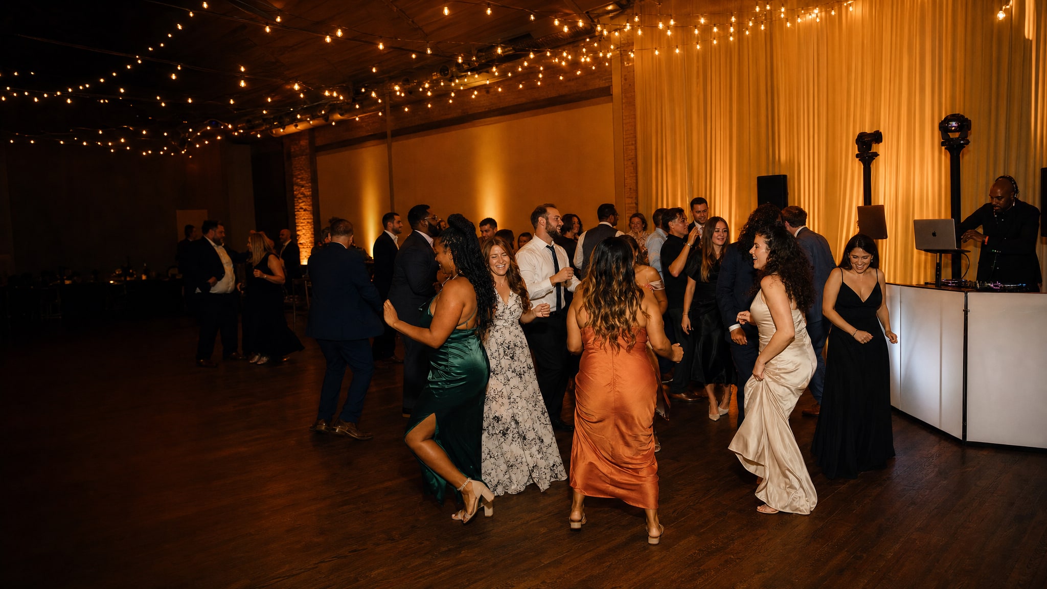 Wedding guests dancing while a DJ plays at an evening reception