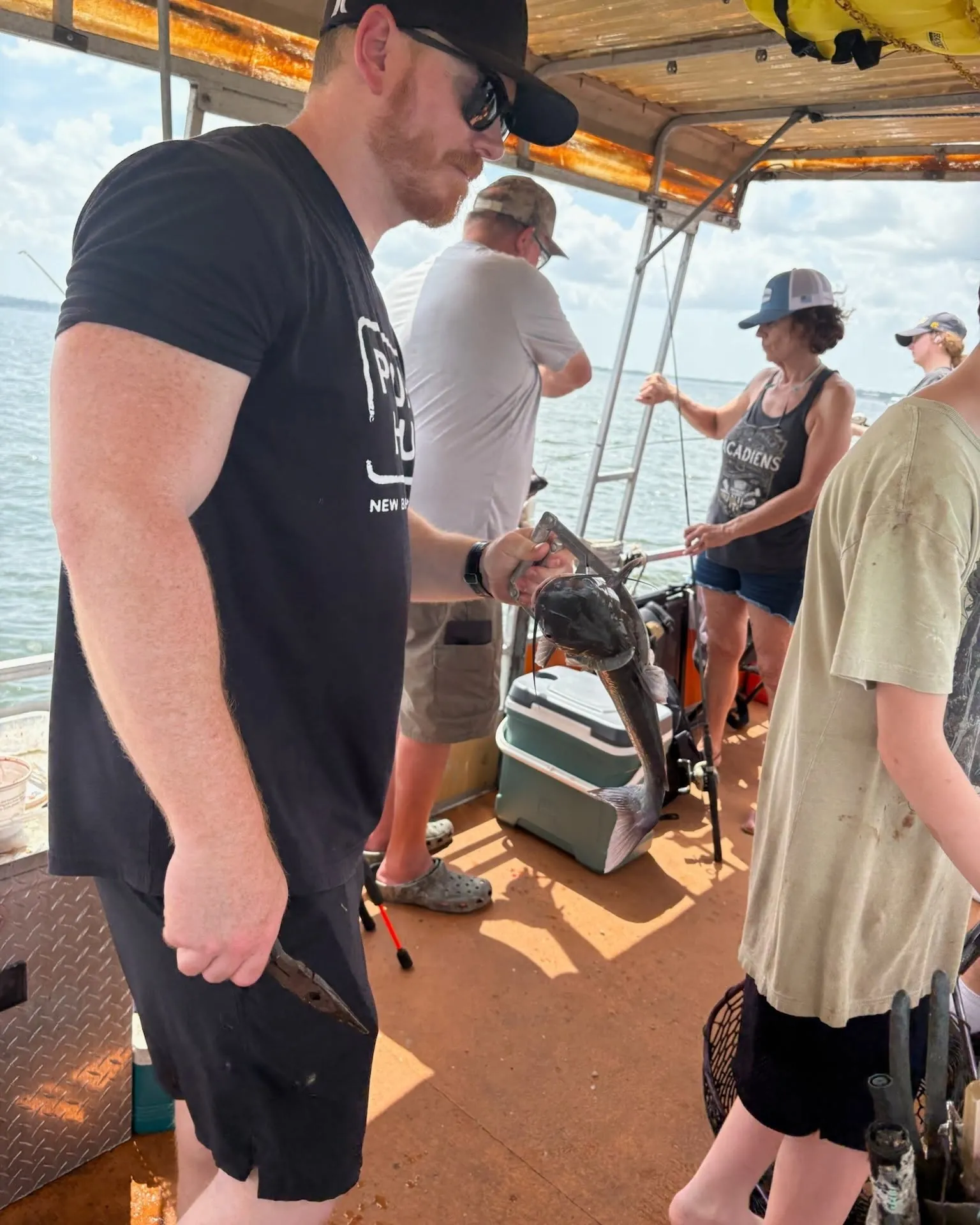 Guests fishing together on a covered Lake Conroe boat with a catfish. Lake Conroe Fishing Guide - Billy Mills