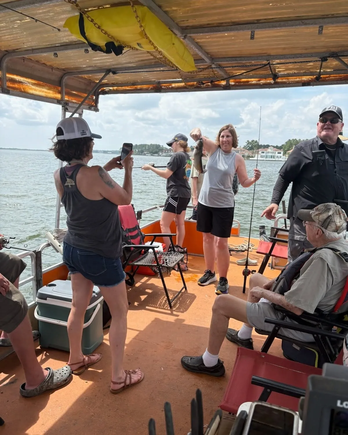 Family and guests fishing from a covered boat on Lake Conroe. Lake Conroe Fishing Guide - Billy Mills