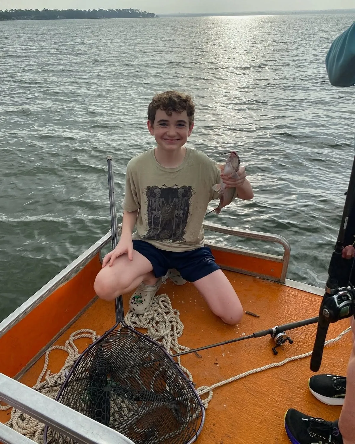 Young angler kneeling with a fish in a landing net. Lake Conroe Fishing Guide - Billy Mills