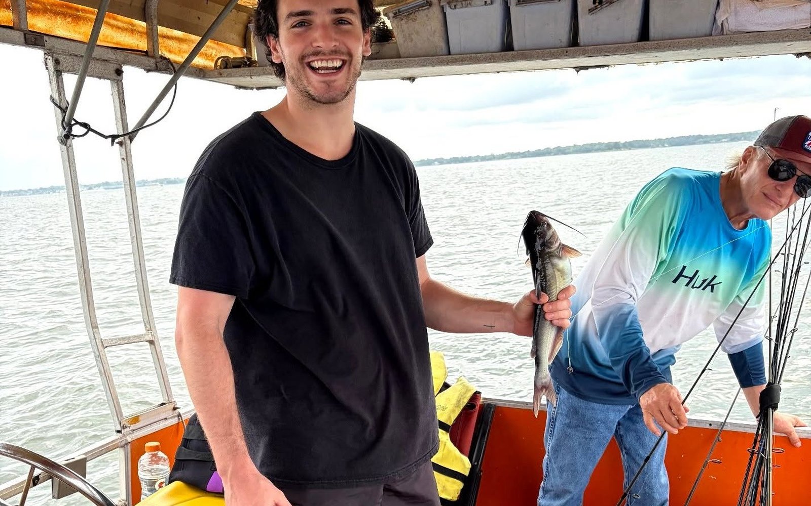 Guest holding a catfish while Billy prepares fishing gear on Lake Conroe. Lake Conroe Fishing Guide - Billy Mills