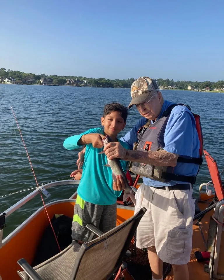 Billy helping a young angler with a fishing rod on Lake Conroe. Lake Conroe Fishing Guide - Billy Mills