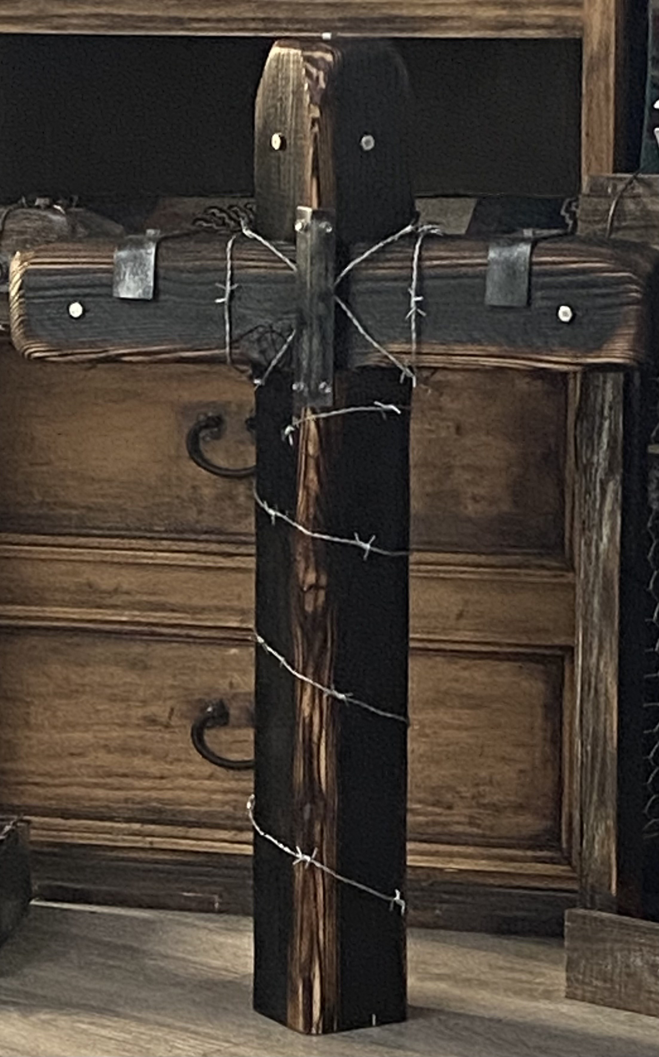Blackened handmade wooden cross displayed indoors