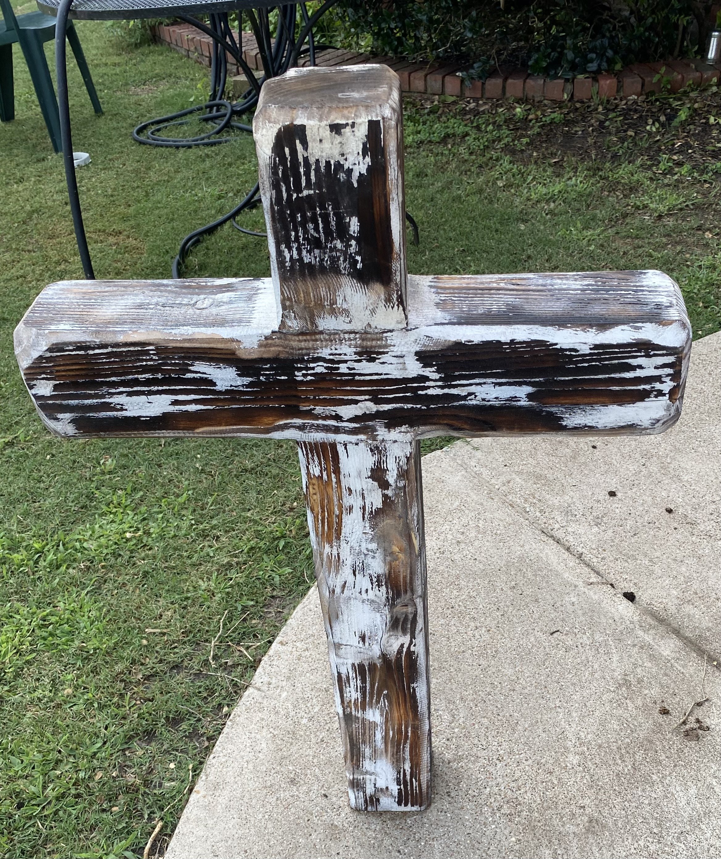 Whitewashed handmade wooden cross displayed outside