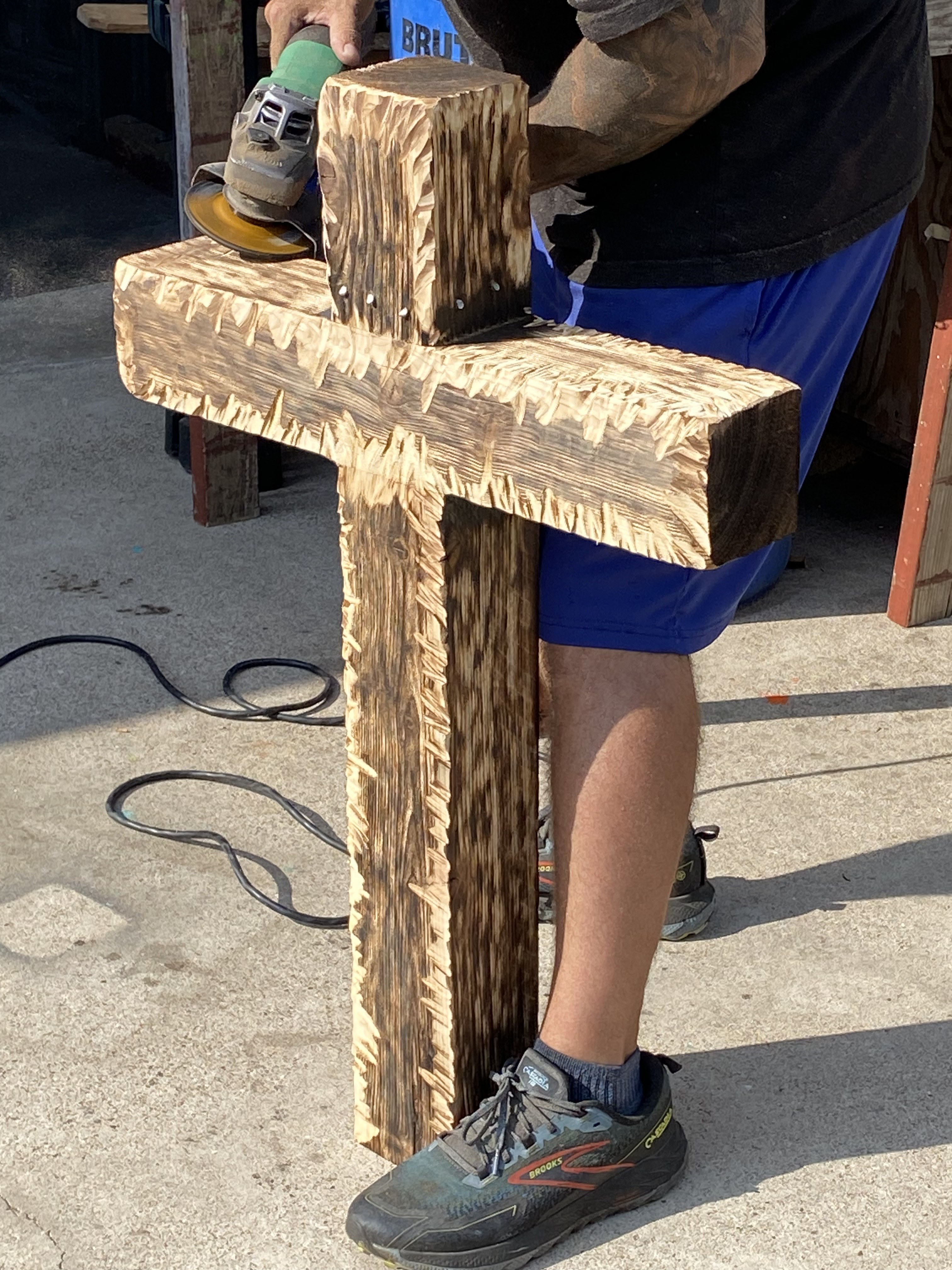 Maker shaping a handmade wooden cross with carved texture