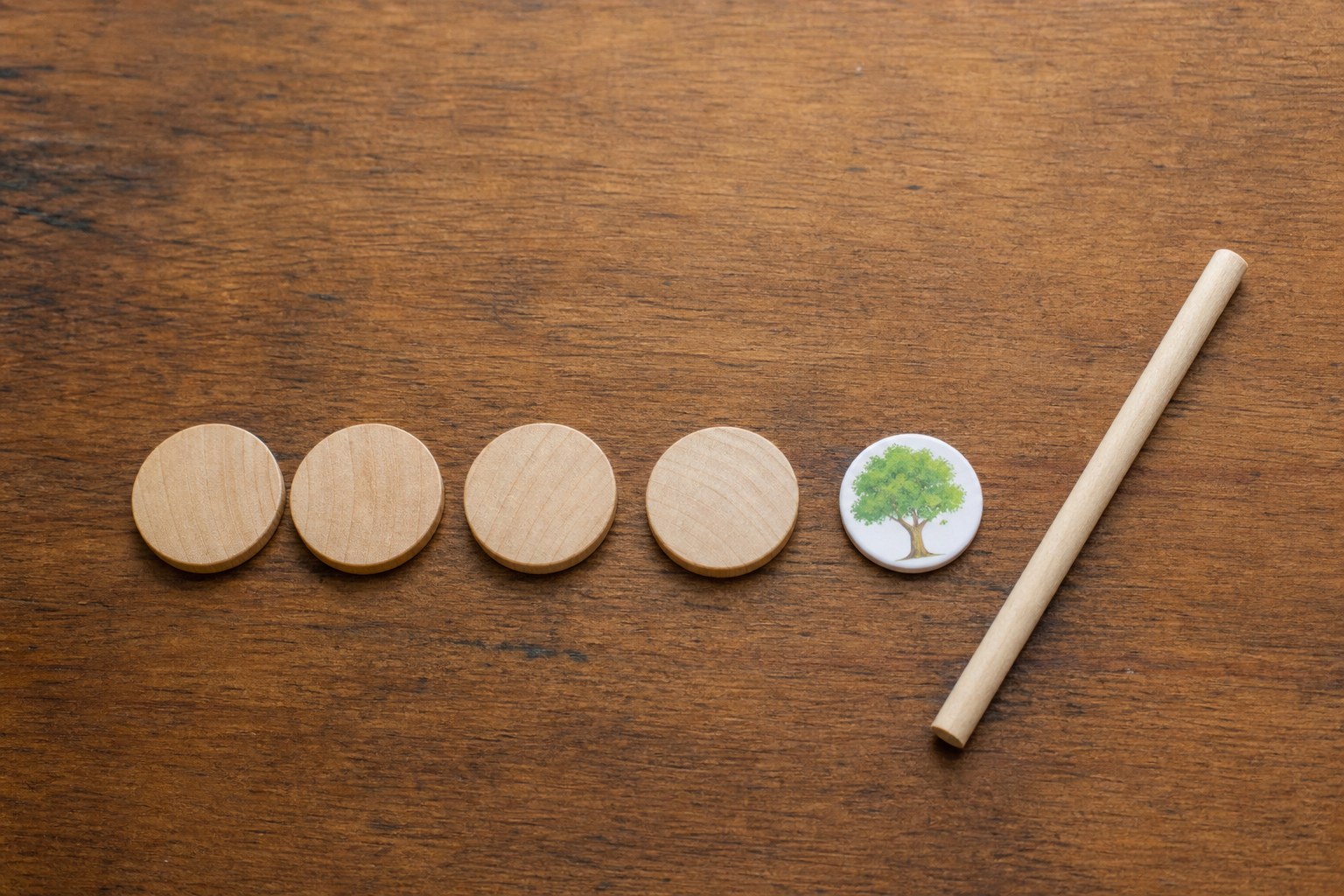Four wooden counters in a row beside a picture token and pointer.