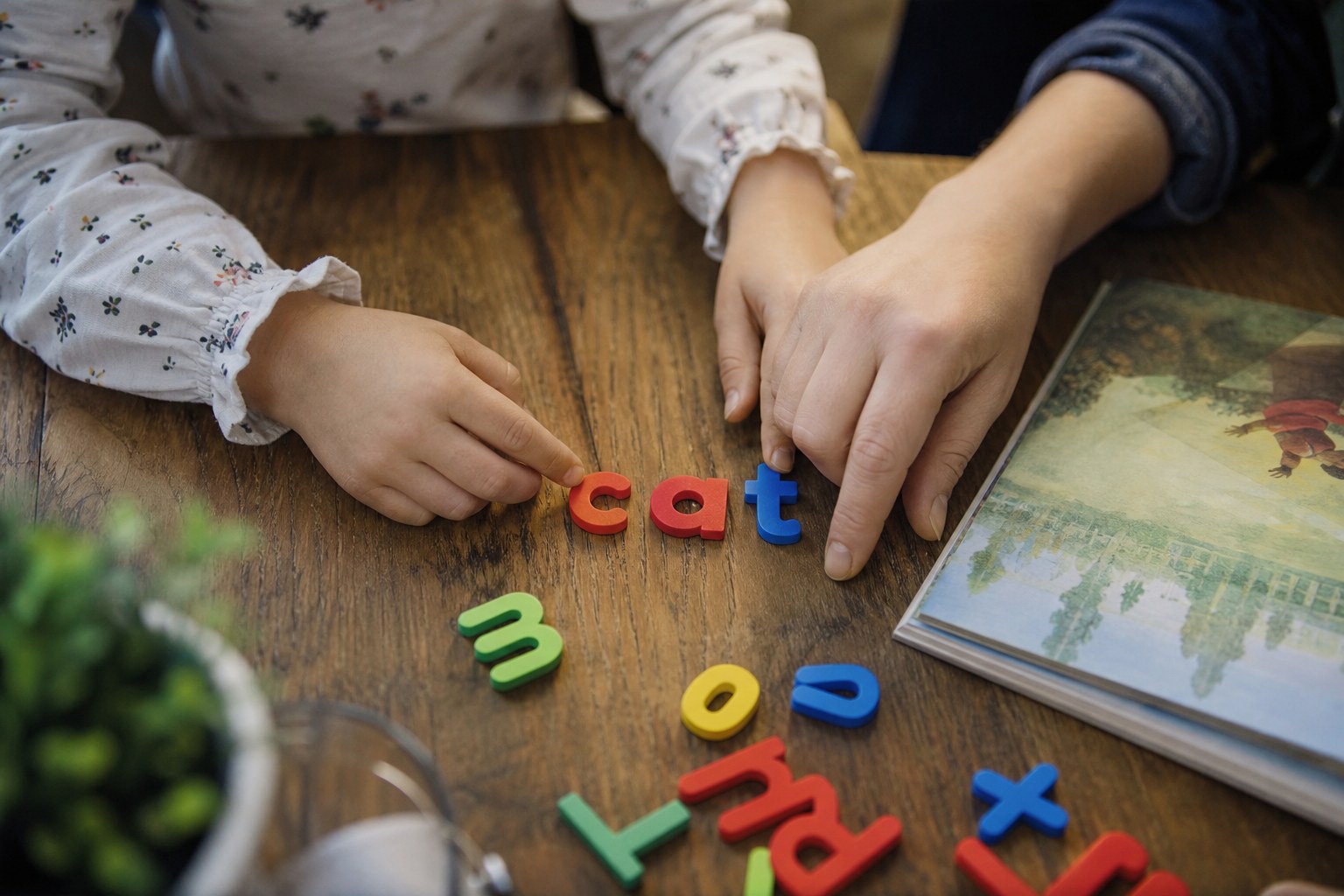 An adult and child arranging letter tiles to make a short word.