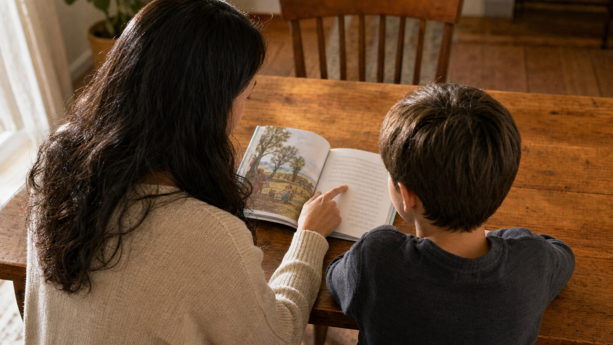 An adult and child reading a book together at a table.