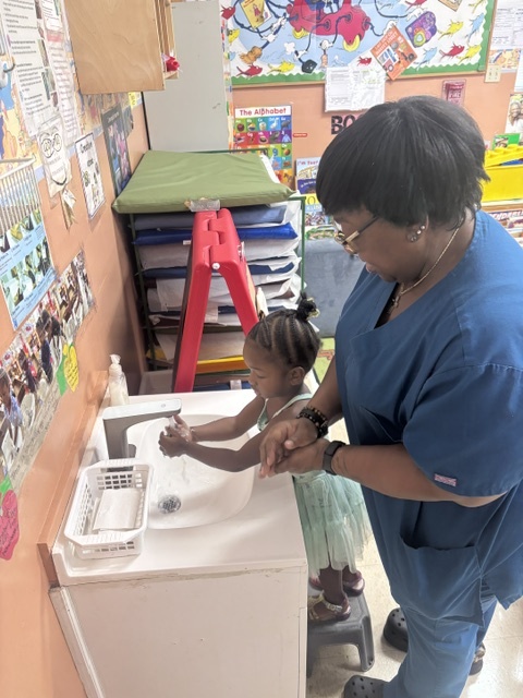 An adult helping a child wash her hands at Peek-A-Boo