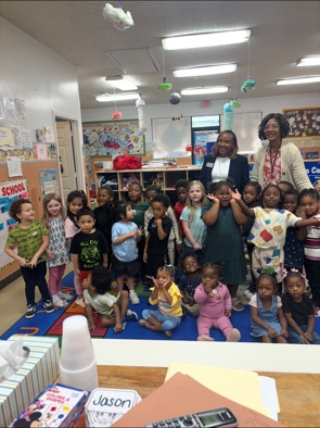 Children and adults posing together in a Peek-A-Boo classroom