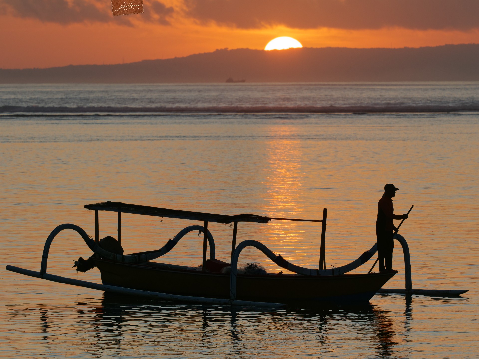 A fisherman makes his way out to see as the sun rises over the Indian Ocean. Bali, Indonesia.