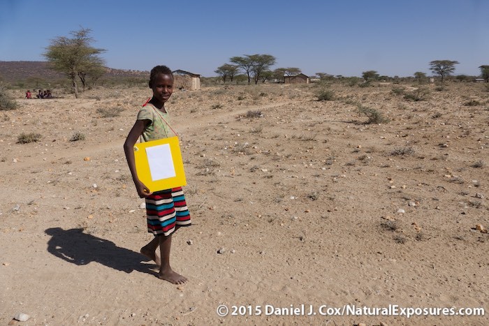 A young Samburu girl shows how easy it is to carry her new Outpostz Lap Desk to and from school. Kenya