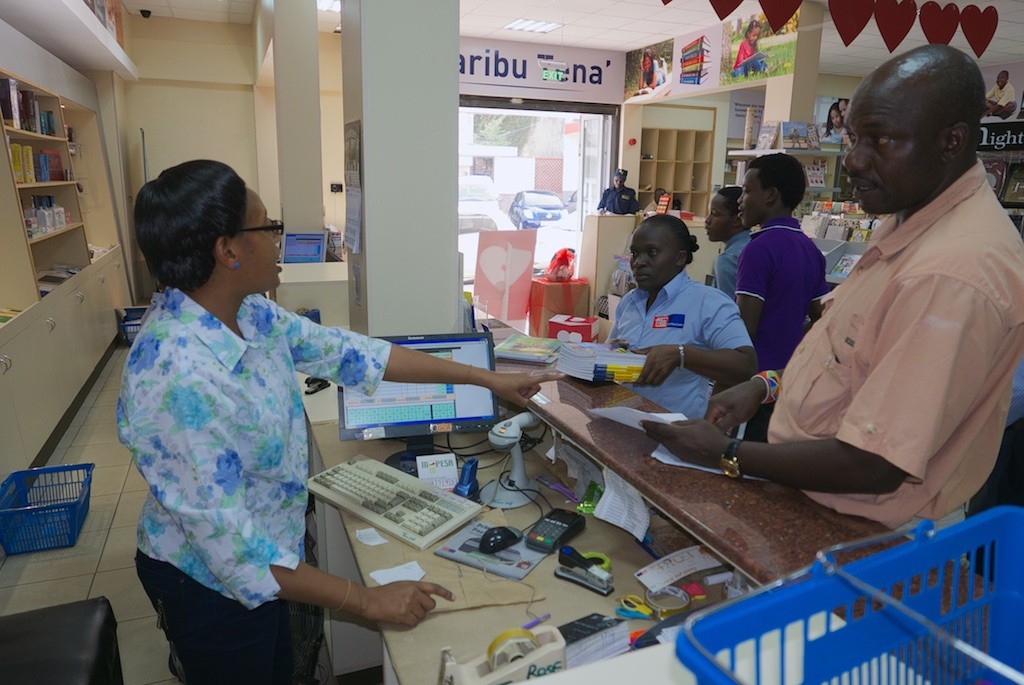 Henry Miwani stands over the cashier checking each book is added to the list with no errors. Kenya. LumixLX100