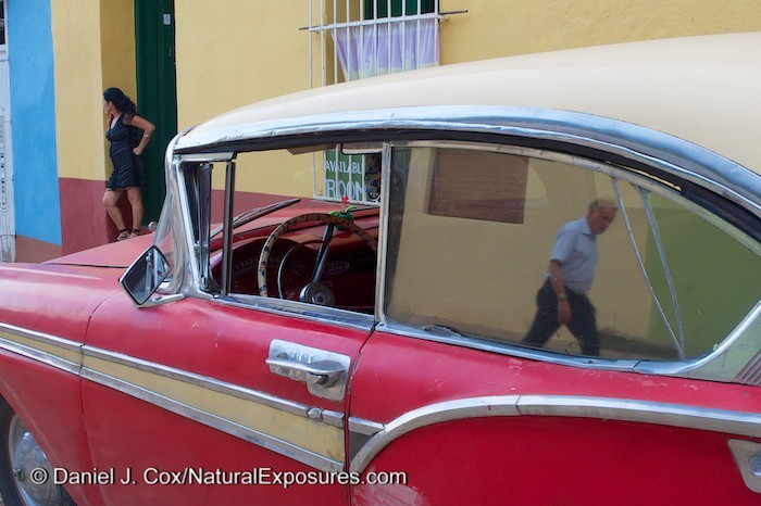 A man passing by an old car is reflected in the window on the streets of Trinidad, Cuba. 