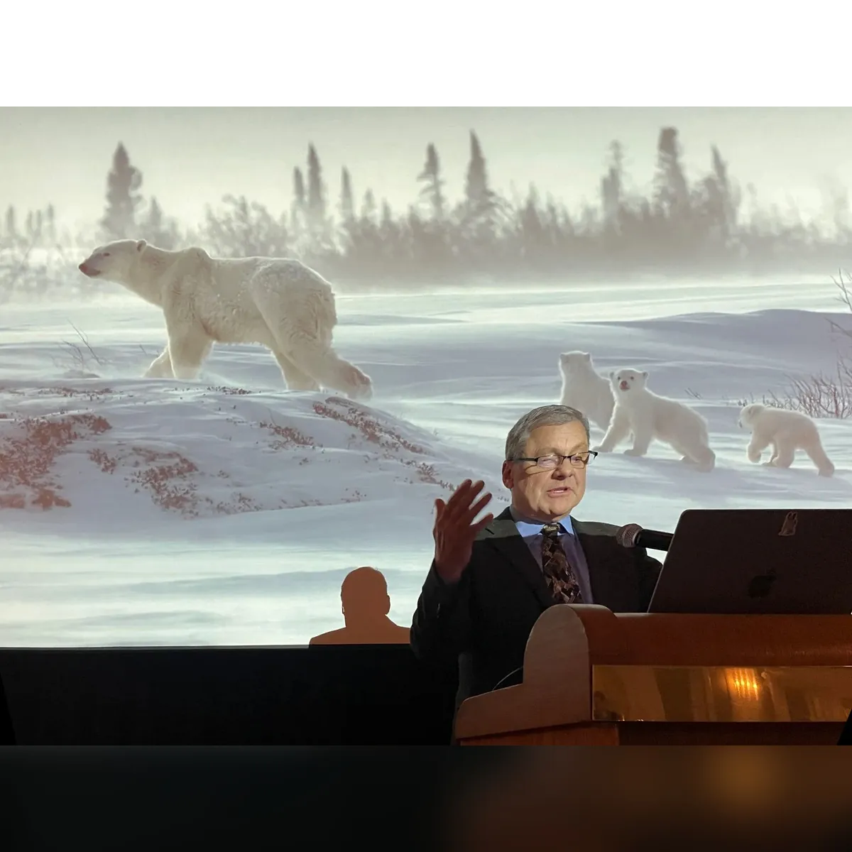 Daniel J. Cox presenting beneath a polar bear photograph