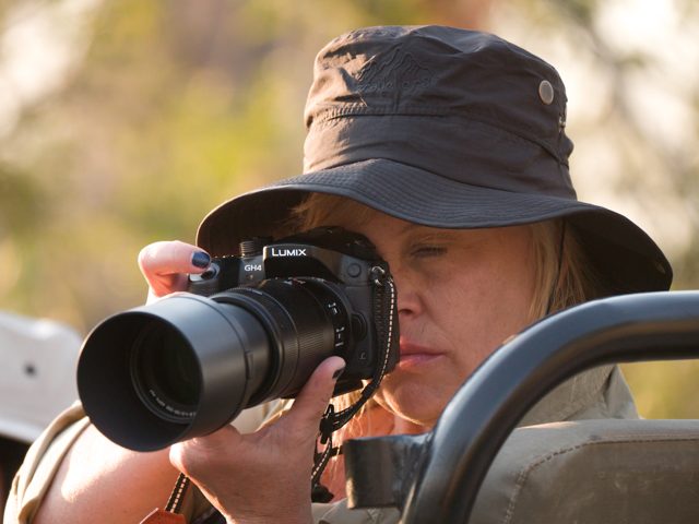 NE Explorer wearing a sun hat and photographing from a safari vehicle