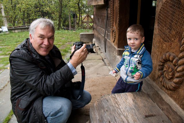 NE Explorer photographing beside a child and a carved doorway