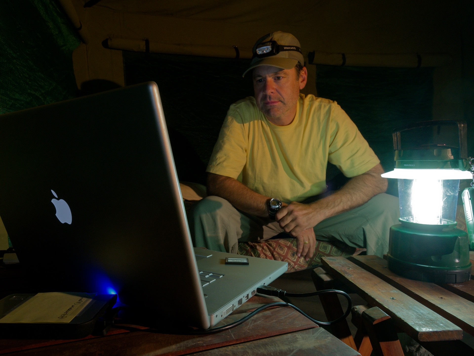 Photographer reviewing images by lantern light in a field tent