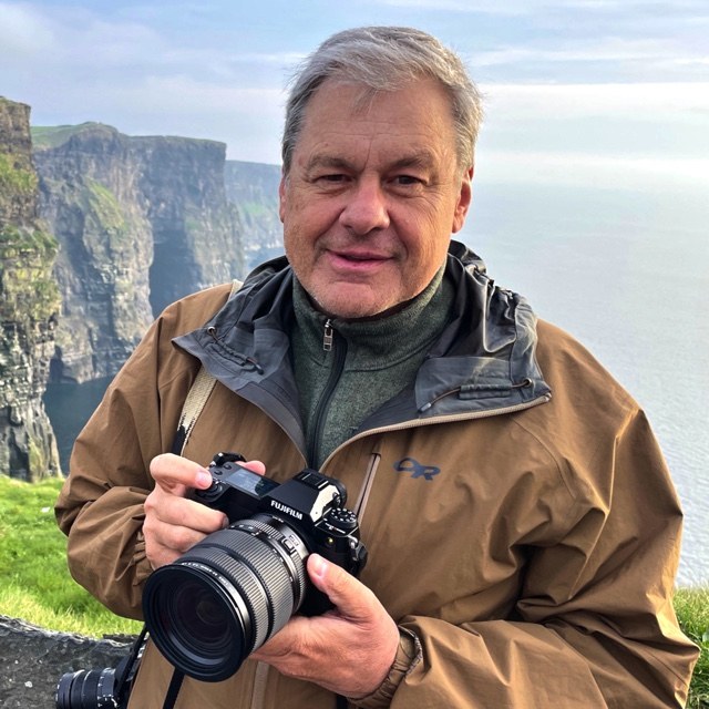 Daniel J. Cox holding a camera in the field