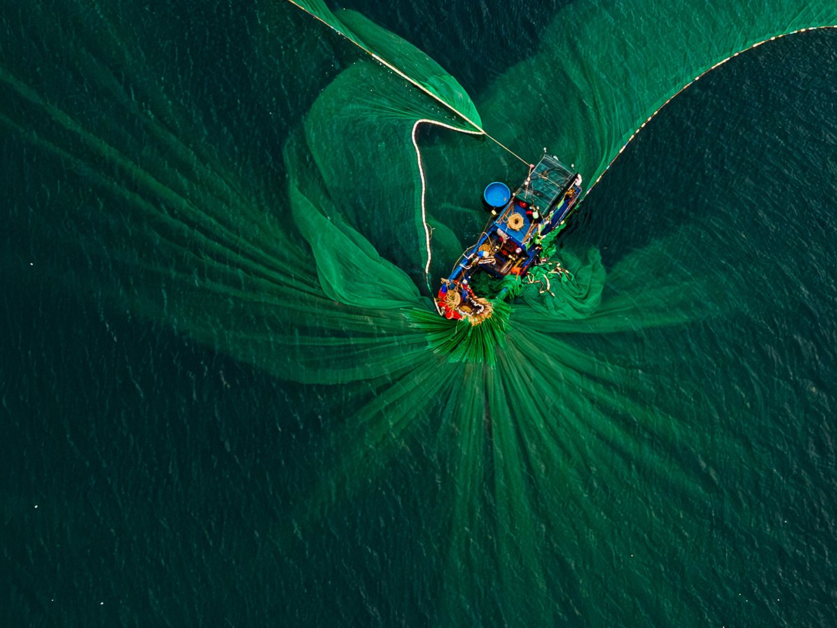 Fishing boat surrounded by sweeping green fishing nets in Vietnam